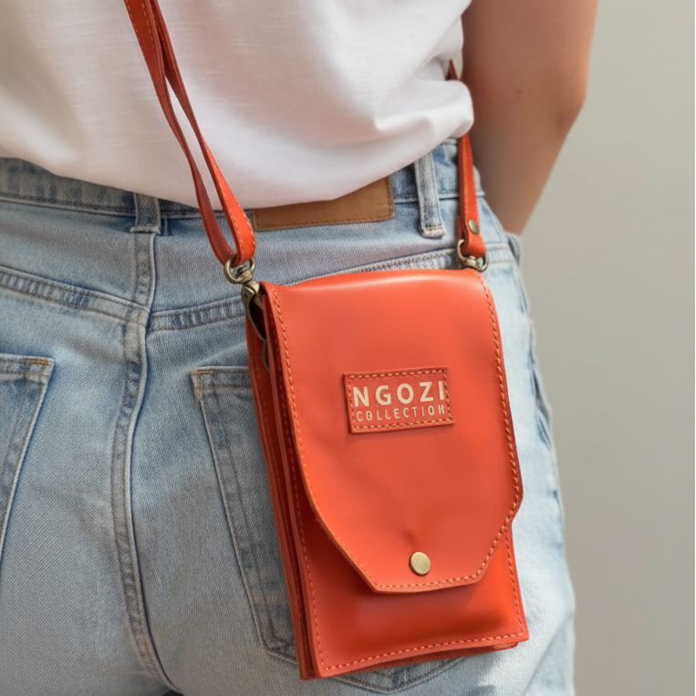 Woman wearing Ngozi Collection coral leather phone sling