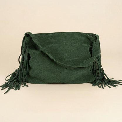 Green suede handbag with fringes on a beige background
