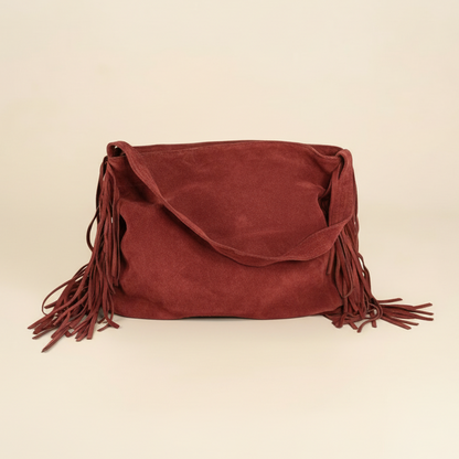 rich red suede handbag with fringes on a beige background